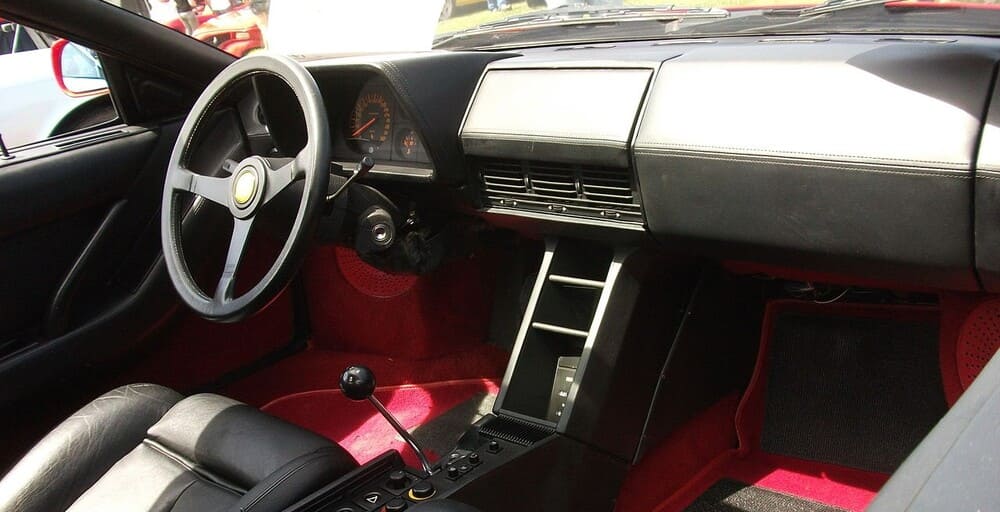 Interior simple del Ferrari Testarossa en sus primera generaciones, con tonos negros y rojos